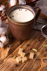 Obraz na płótnie Canvas Tea with milk, cream and spices on a wooden background. Masala tea.