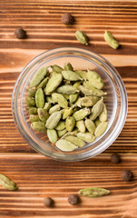 Cardamom in a glass plate on a wooden background. Close-up
