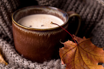 Masala tea in a scarf on a wooden table. Autumn. Autumn foliage.