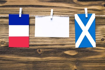 Hanging flags of France and Scotland attached to rope with clothes pins with copy space on white...
