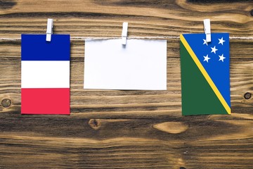 Hanging flags of France and Solomon Islands attached to rope with clothes pins with copy space on...