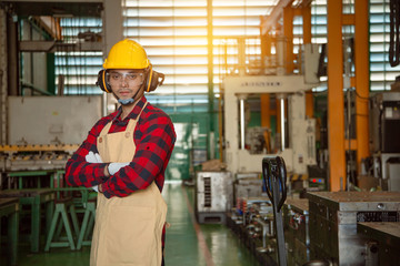 Portrait of young male factory worker standing with arms crossed in  production factory