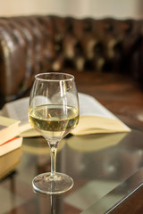 English retro style room with leather chair, open book and glas of white wine