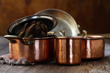 copper utensils, pots, ladle and pan on wooden background