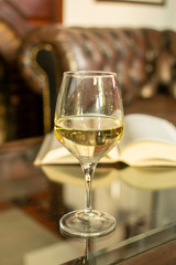 English retro style room with leather chair, open book and glas of white wine