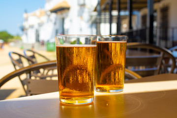 Cold amber color light spanish beer served in glass in outdoor cafe in town on sand, El Rocio in Andalusia, Spain