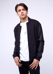 Young man in jeans, black bomber jacket on white background.