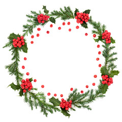 Holly and juniper leaf wreath with loose red berries for winter and Christmas on white background with copy space. Traditional symbol for the festive season.