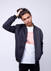 Young man in jeans, black bomber jacket on white background.