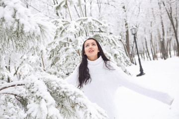 sweet pretty girl in white sweater and a winter park