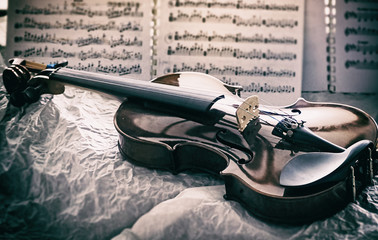 The abstract art design background of wooden violin,put in front blurred note sheet,vintage and art tone,blurry light around