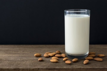 Almonds and almond milk on wooden table with copy space .Black background