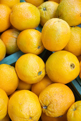 Bright yellow fresh oranges in plastic boxes at farmer's market or grocery store aerial view. May be used for background. Top view.