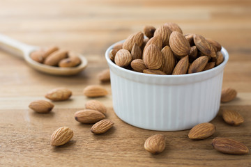 Almonds in white porcelain bowl on wooden table
