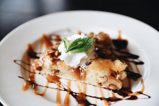 Pie with whipped cream, mint, caramel and chocolate sauce served on plate