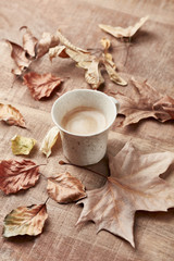 Fototapeta na wymiar Mug of coffee and autumn leaves. Rustic wooden background. Copy space. 