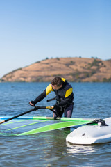 Obraz premium Windsurfer checking his sail and board equipment.