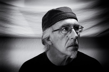 Adult male wearing cap, looking right. Black and white portrait of man wearing eyeglasses, mustache...