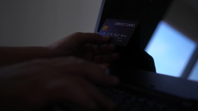 hacker with credit card, theft holding credit cards on laptops using data password in unauthorized shopping for payments, hacking in cyber crime security concept
