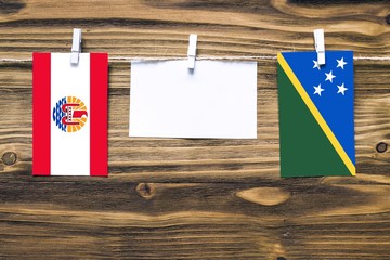 Hanging flags of French Polynesia and Solomon Islands attached to rope with clothes pins with copy...