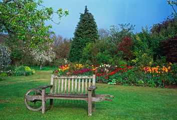 Colourful spring border of Tulips and an ususual garden seat at a Country House Garden