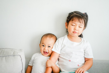 Little sister hugging her baby brother.Toddler kid meeting new sibling. Cute girl and baby boy relax at home in Japan.Family with children at home. Love, trust and tenderness.
