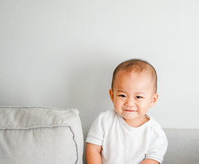 Fototapeta premium Cute adorable one year seven month old baby boy.Closeup of adorable asian boy child, little baby boy on sofa at home.