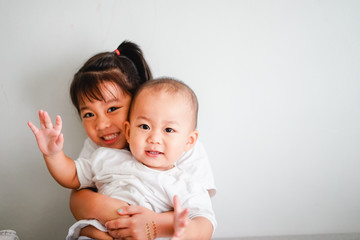 Little sister hugging her baby brother.Toddler kid meeting new sibling. Cute girl and baby boy relax at home in Japan.Family with children at home. Love, trust and tenderness.