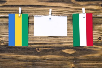 Hanging flags of Gabon and Hungary attached to rope with clothes pins with copy space on white note...