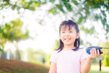 4 years little asian girl playing with walkie-talkie on the park.Happy girl smile and laughing when she plays outside in a playground with a toy walkie talkie radio.