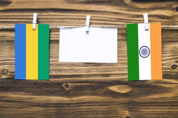 Hanging flags of Gabon and India attached to rope with clothes pins with copy space on white note...