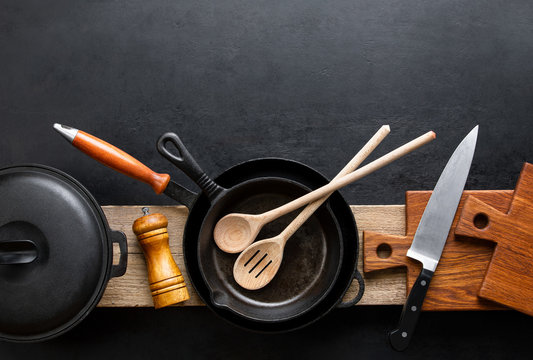 Kitchen utensils dark background with cast iron black kitchenware