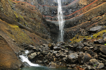 Hengifoss Canyon and Waterfall, the third highest waterfall in Iceland is surrounded by basaltic strata with red layers of clay between the basaltic layers