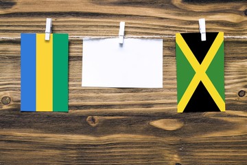 Hanging flags of Gabon and Jamaica attached to rope with clothes pins with copy space on white note...