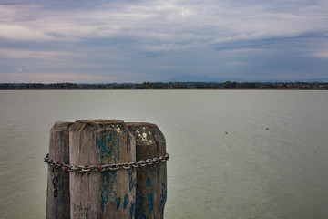 Fototapeta premium Close up of three pillars chained together lake and skyline in the background overcast beautiful skies