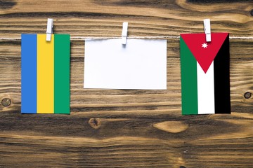 Hanging flags of Gabon and Jordan attached to rope with clothes pins with copy space on white note...
