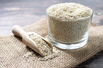 Fresh organic sesame seeds on the sackcloth on dark wooden table. Healthy and tasty food concept.