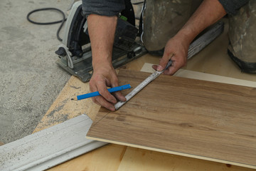 Worker measures and saws off fragments of steps for stairs - obrazy, fototapety, plakaty