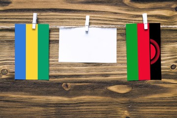Hanging flags of Gabon and Malawi attached to rope with clothes pins with copy space on white note...