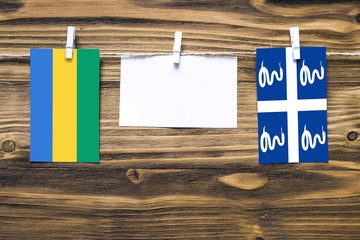 Hanging flags of Gabon and Martinique attached to rope with clothes pins with copy space on white...