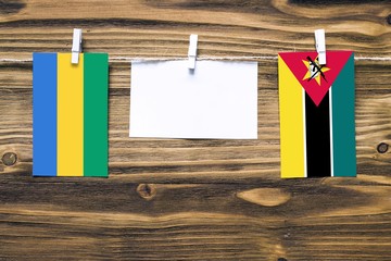 Hanging flags of Gabon and Mozambique attached to rope with clothes pins with copy space on white...