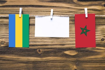 Hanging flags of Gabon and Morocco attached to rope with clothes pins with copy space on white note...