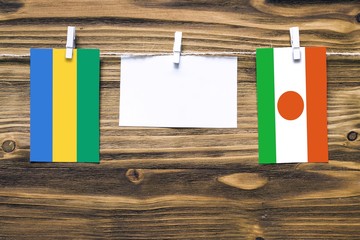 Hanging flags of Gabon and Niger attached to rope with clothes pins with copy space on white note...