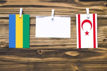 Hanging flags of Gabon and Northern Cyprus attached to rope with clothes pins with copy space on...