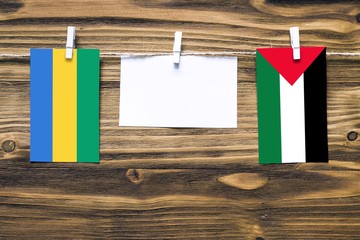 Hanging flags of Gabon and Palestine attached to rope with clothes pins with copy space on white...