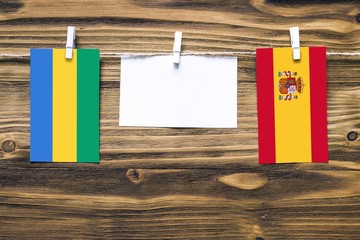 Hanging flags of Gabon and Spain attached to rope with clothes pins with copy space on white note...