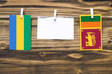 Hanging flags of Gabon and Sri Lanka attached to rope with clothes pins with copy space on white...