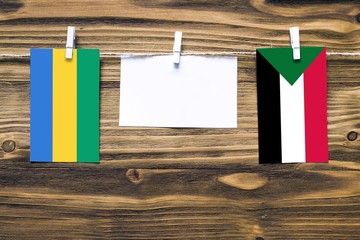 Hanging flags of Gabon and Sudan attached to rope with clothes pins with copy space on white note...