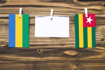 Hanging flags of Gabon and Togo attached to rope with clothes pins with copy space on white note...