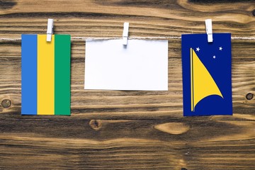 Hanging flags of Gabon and Tokelau attached to rope with clothes pins with copy space on white note...